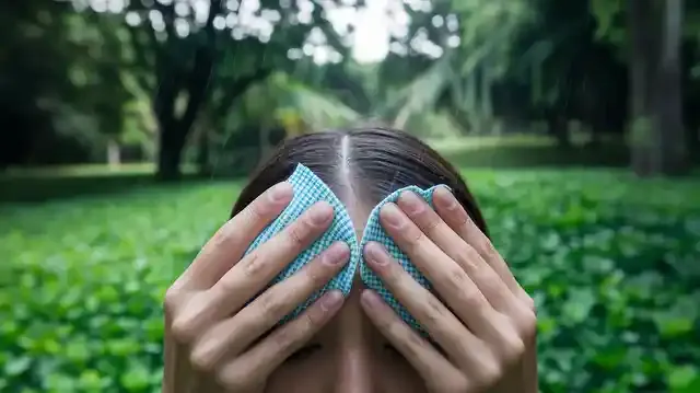 Causes Of Too Much Sweating And How To Fix - Person managing excessive sweating outdoors with a cloth