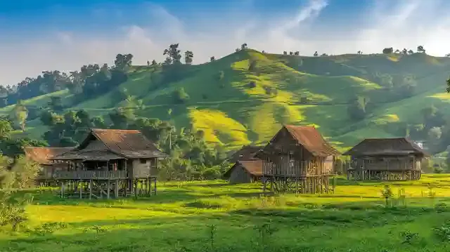 When To Visit Laos For Great Weather And Low Prices - Laotian countryside with green hills and traditional houses